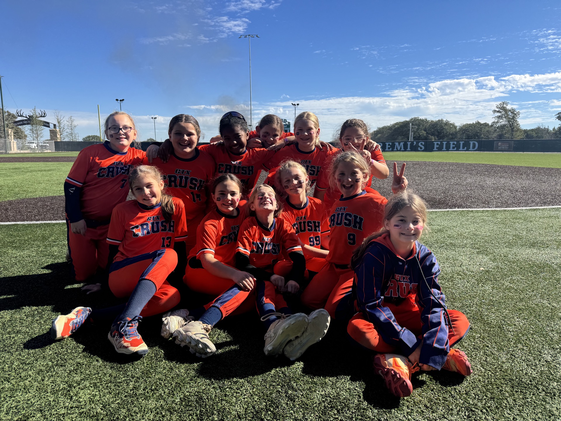 GTX Crush players together on the softball field in orange jerseys